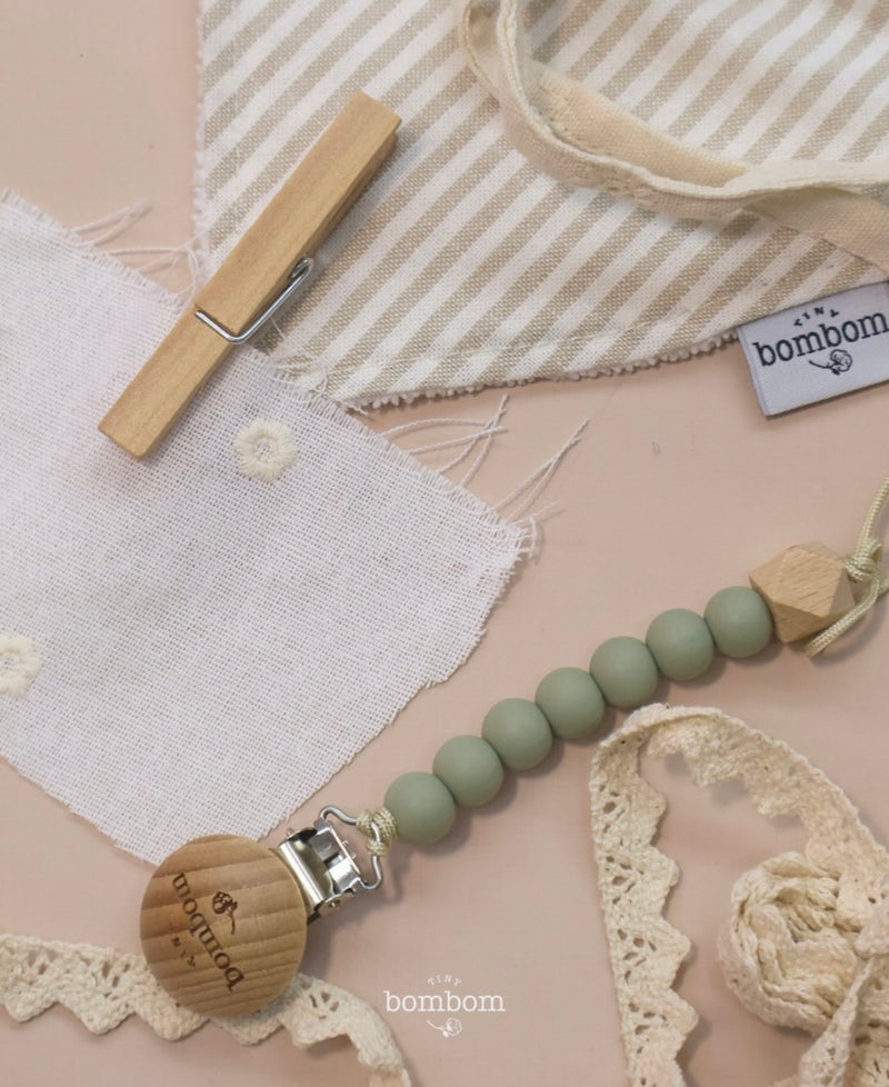 Detalle de telas, encaje y portachupón de madera con cuentas verdes